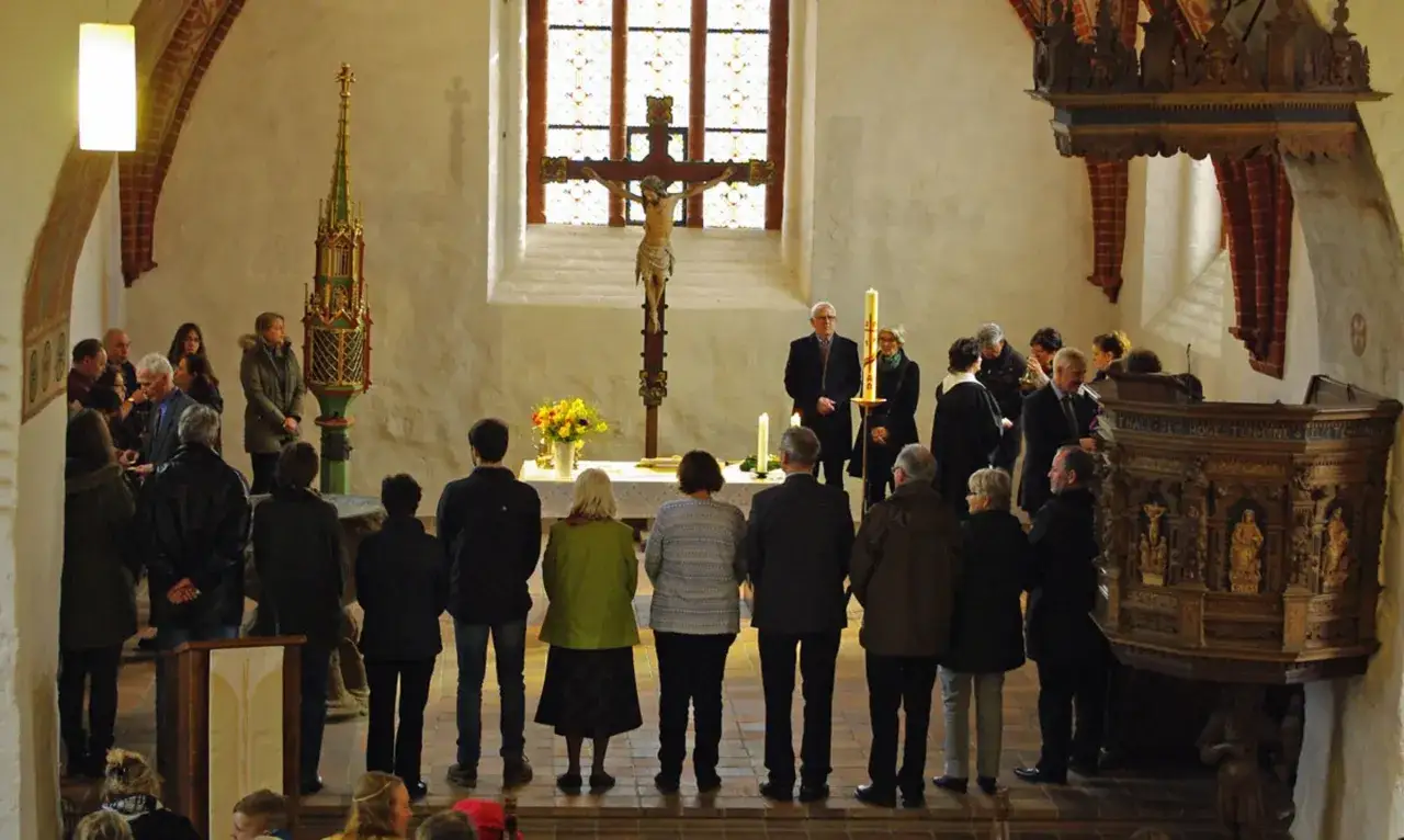 Menschen stehen in einer Kirche vor einem Kreuz. Eine Frau in Grün steht vorn. Kommt, sagt es allen weiter.
