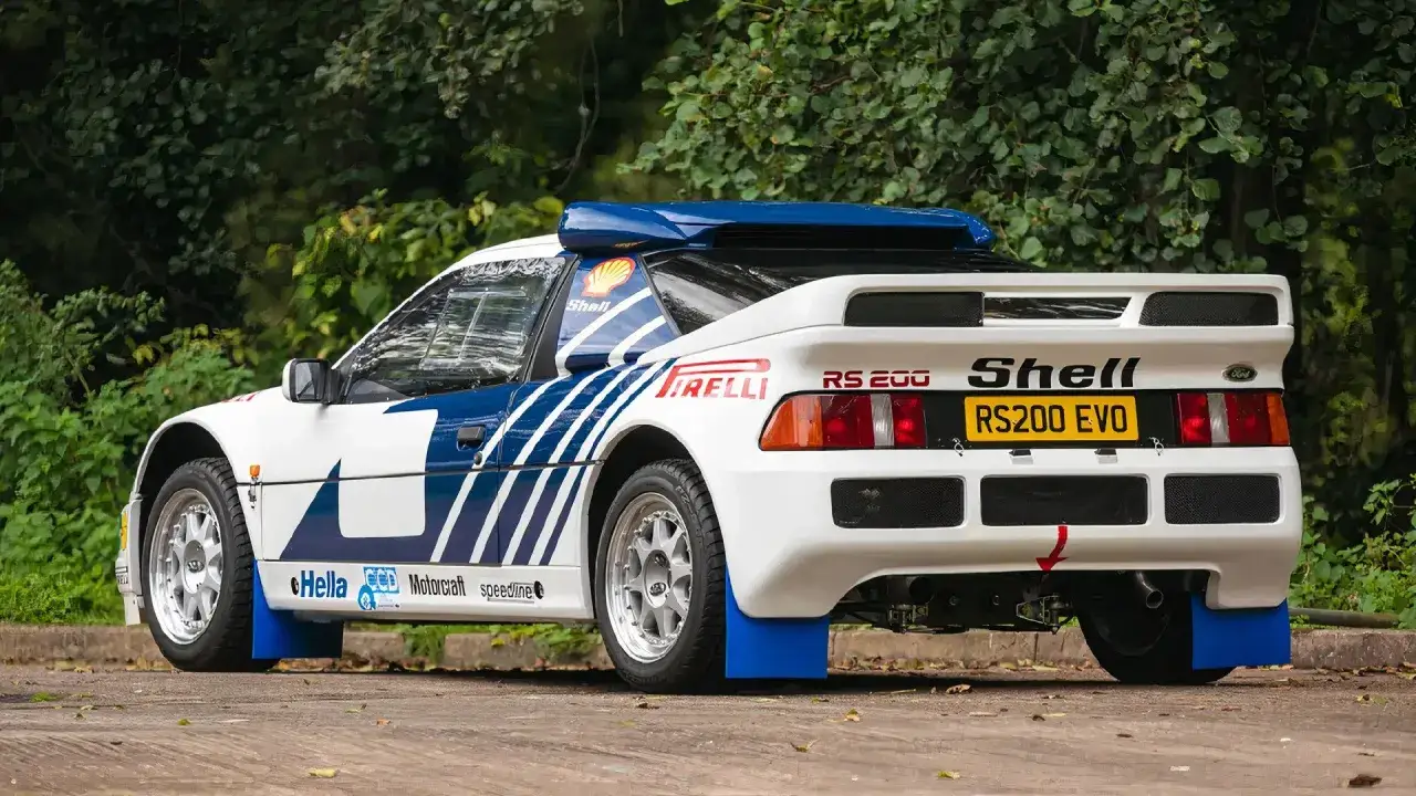 Vit Ford RS200 EVO med bl&aring;a detaljer och rallydekaler, redo f&ouml;r &auml;ventyr i skogen.