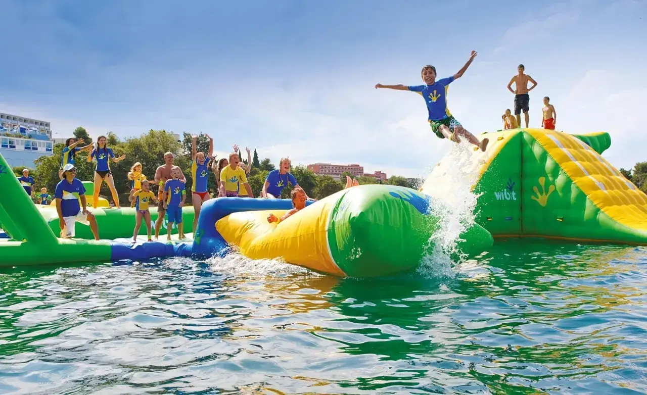 Des enfants s'amusent dans un aquapark gonflable près de Paris, sautant et glissant sur des structures colorées dans l'eau.