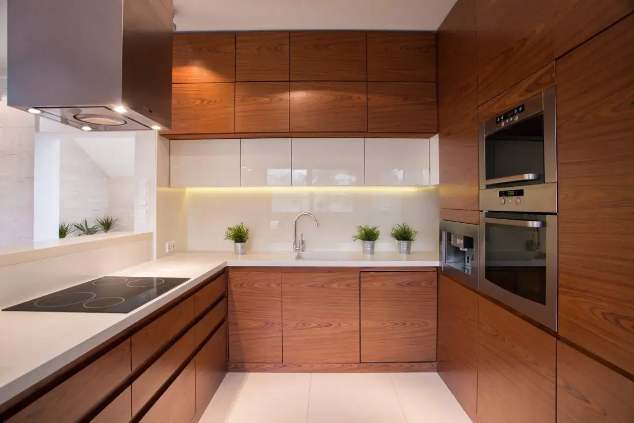 Cocinas peque&ntilde;as y bonitas con gabinetes de madera y encimeras blancas. Incluye estufa, fregadero, horno y cafetera.