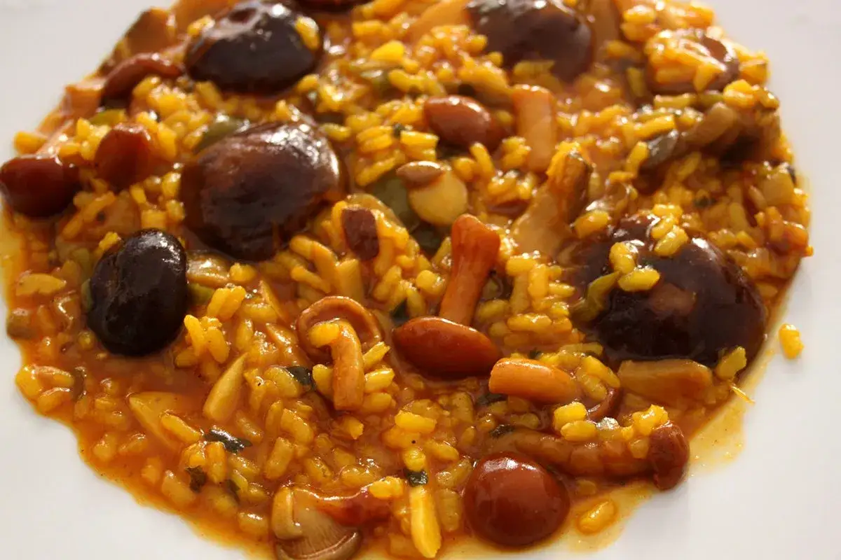 Arroz con setas, un plato reconfortante con arroz amarillo, champiñones oscuros y setas de temporada en una salsa sabrosa.