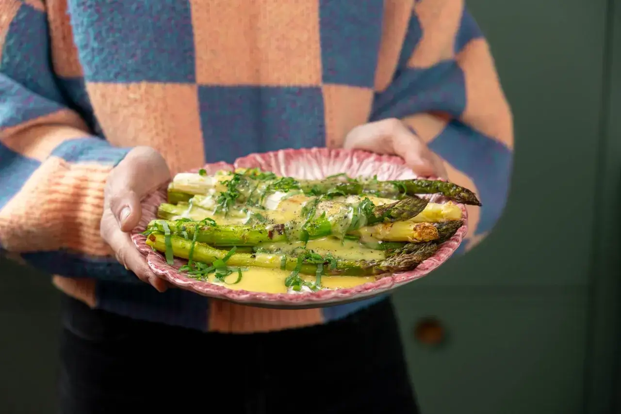En tallrik med grön och vit sparris, dränkt i en krämig hollandaisesås och toppad med färska örter. Ett perfekt sparris recept för våren.