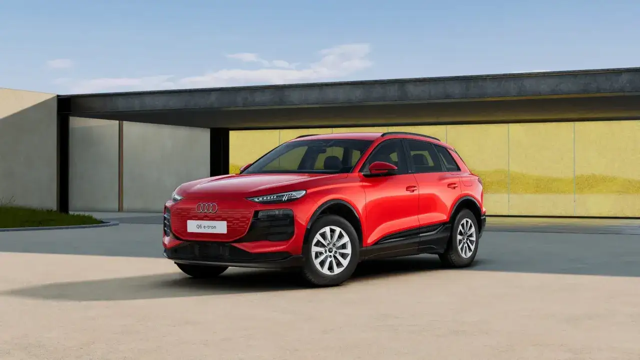 Czerwony Audi Q6 e-tron przed nowoczesnym budynkiem. Sprawdź atrakcyjną audi q6 e-tron cenę!