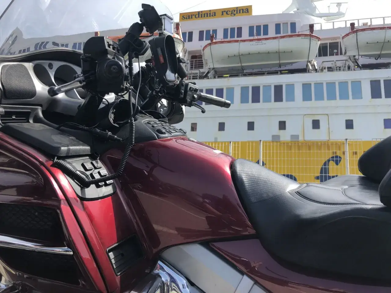Czerwony motocykl czeka na prom do Sardynii. Sprawdzam korsyka ceny, by zaplanować podróż.