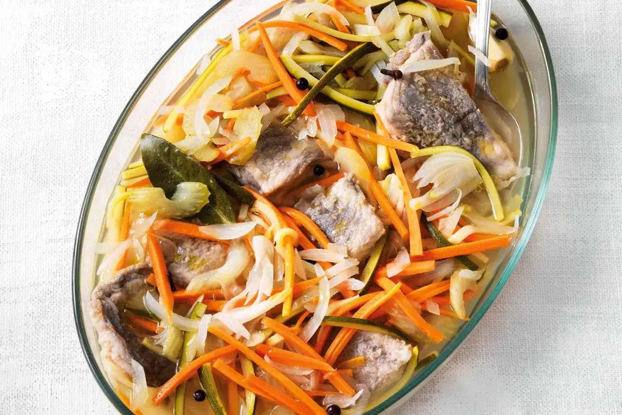 Agoni in carpione, un piatto tradizionale con pesce, carote, cipolle e zucchine julienne, condito con erbe aromatiche e pepe nero.