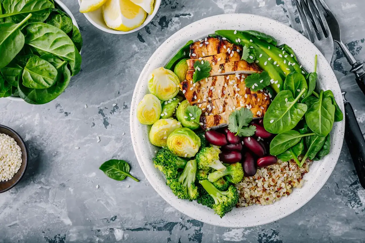 Un'idea gustosa per cosa mangiare a pranzo: pollo grigliato, spinaci freschi, broccoli, cavolini di Bruxelles, fagioli rossi e quinoa.