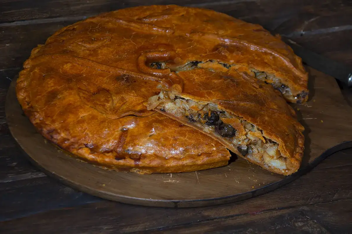 Empanada de bacalao dorada y crujiente, con un relleno generoso de arroz y pasas.