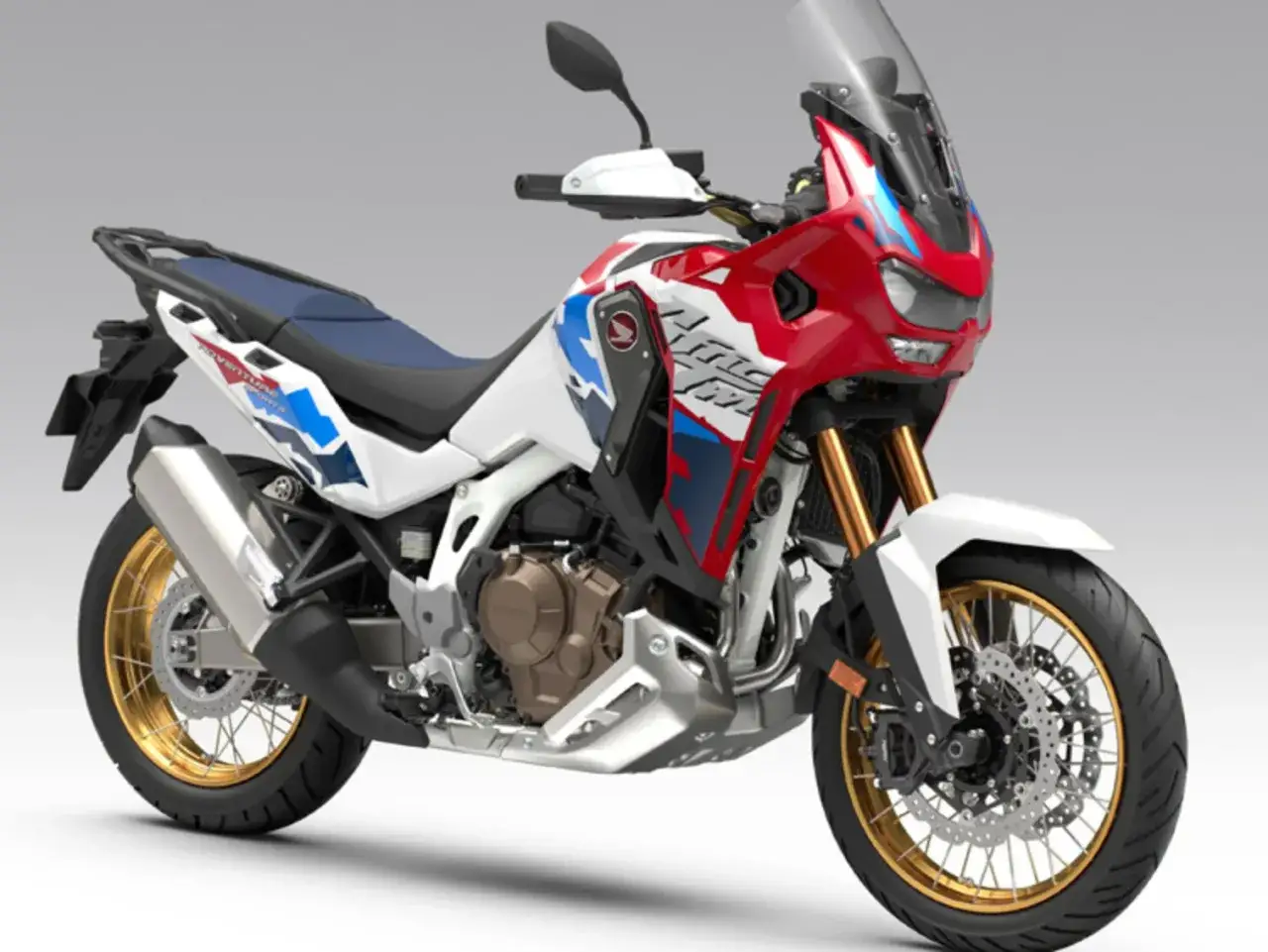 Nowy motocykl Africa Twin w biało-czerwono-niebieskich barwach, gotowy na przygodę.
