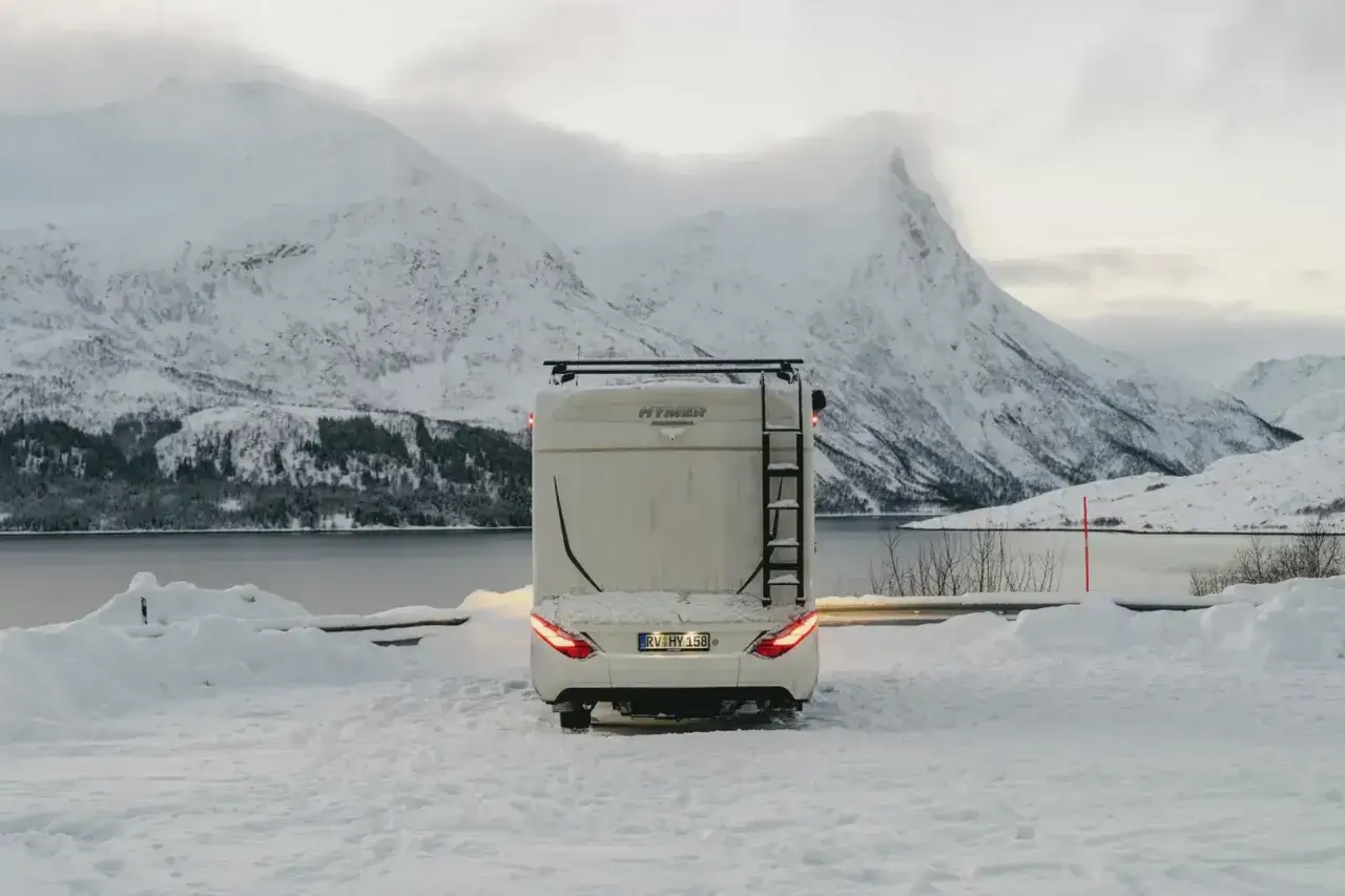 Husbil parkerad i snöig norsk fjällmiljö, redo för att uppleva norrsken i Norge.