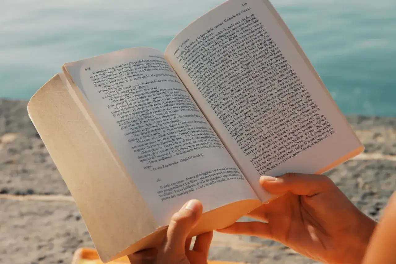 Mani che sfogliano un libro aperto, con pagine piene di nomi siciliani e storie.