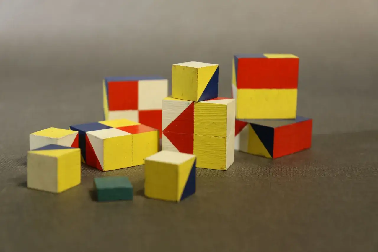 Kolorowe klocki, niektóre z geometrycznymi wzorami, przypominają elementy do budowania, jakby z dziecięcej zabawy, tworząc wizualną skalę Wechslera.