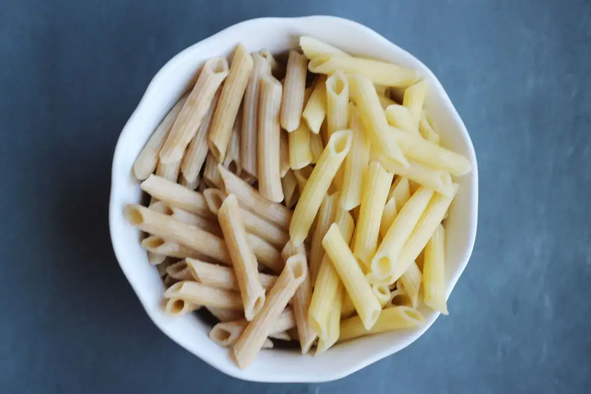 Biała miska z makaronem penne: jasny vs ciemny makaron.