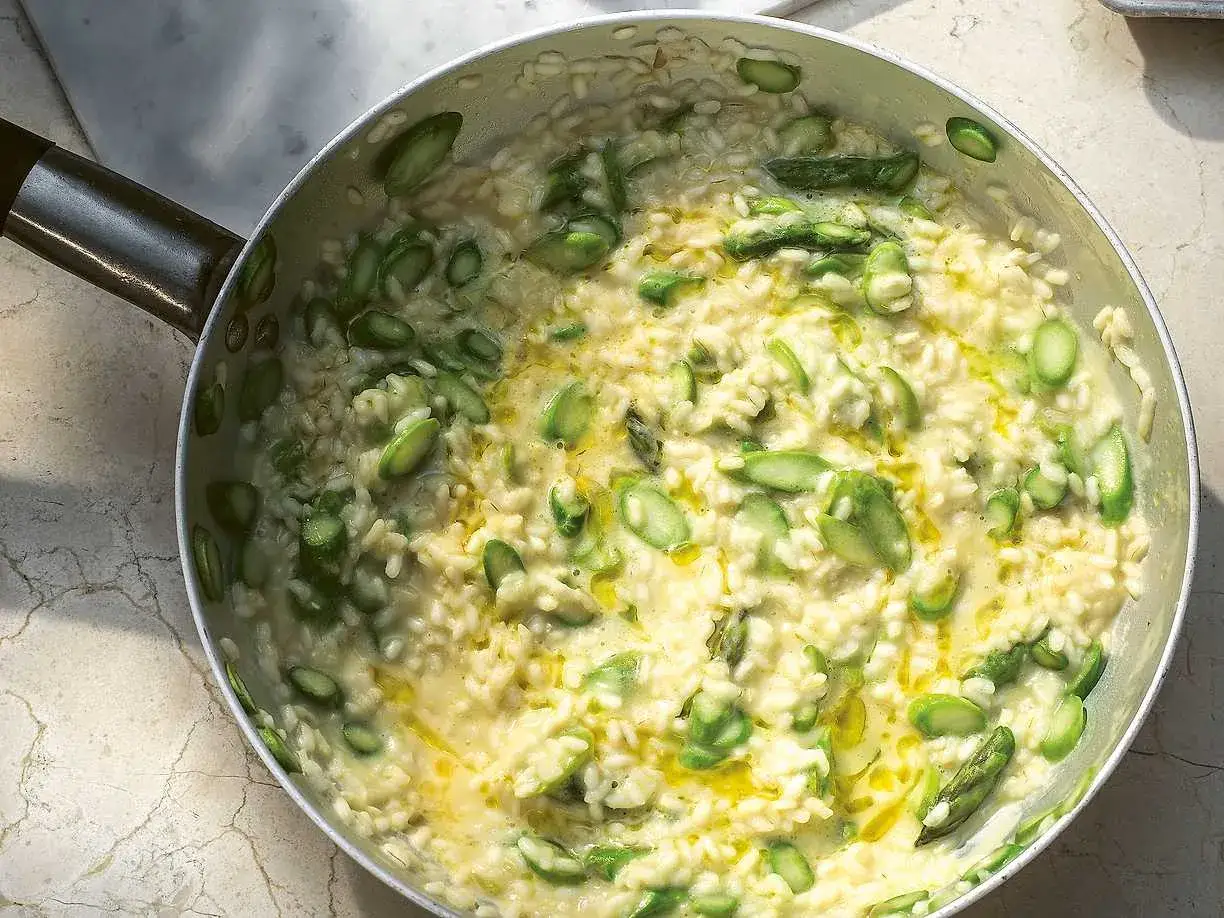 Krämig sparris risotto i en panna, med färska gröna sparrisbitar och en gyllene olja som glänser.