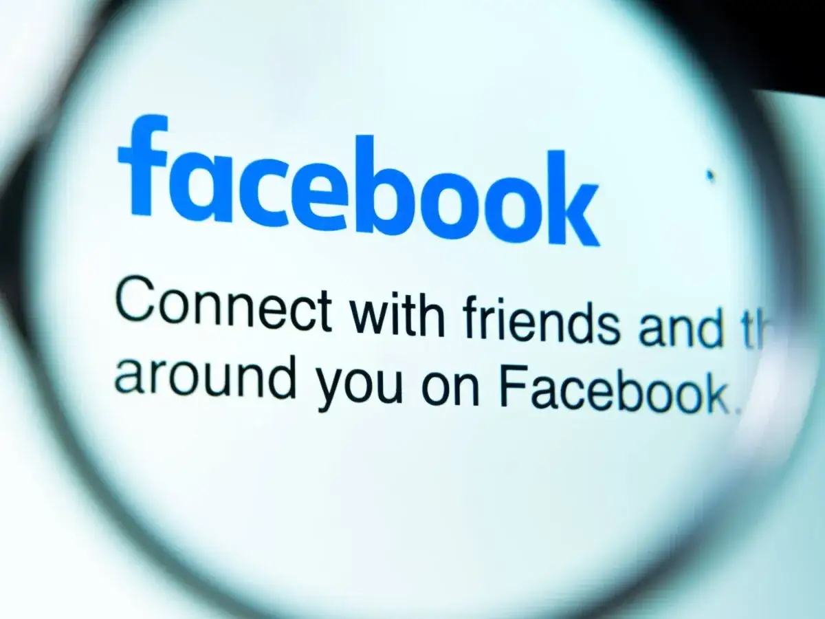 Lupa powiększa logo Facebooka i napis