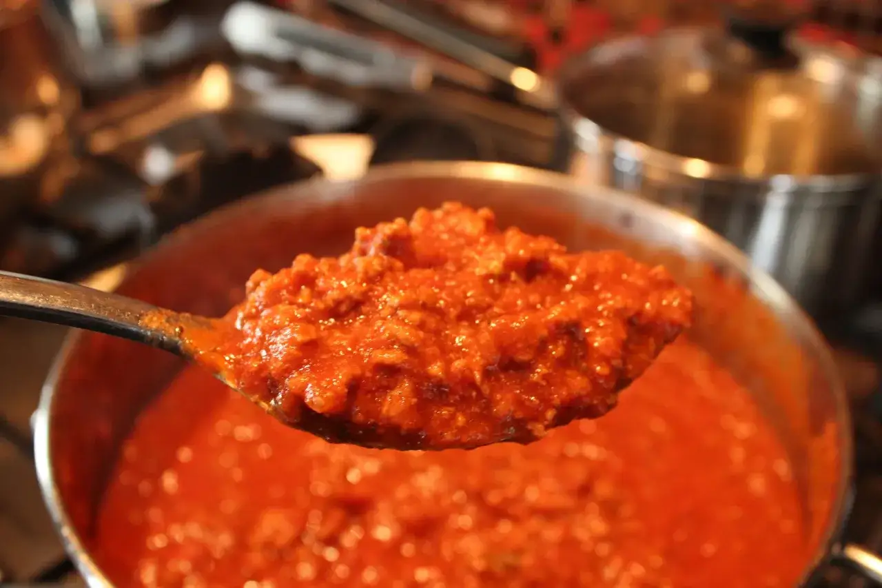 Un cucchiaio pieno di ragù di carne, denso e saporito, pronto per condire la pasta.