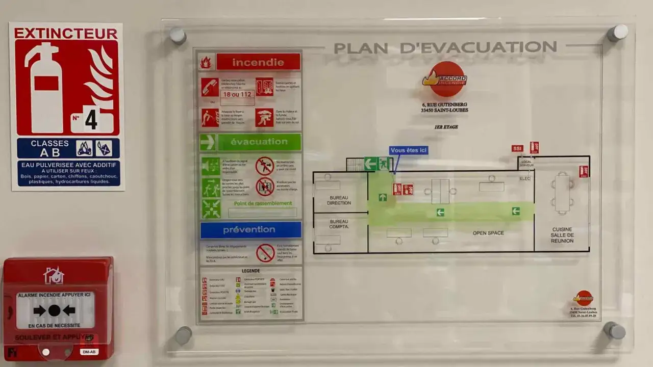 Plan d'&eacute;vacuation indiquant les issues, le point de rassemblement et les extincteurs. Un bouton rouge 