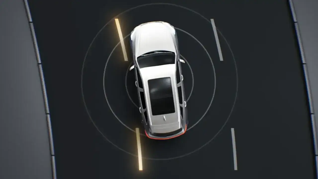 Vista aérea de un coche plateado en una carretera oscura, con círculos concéntricos y líneas amarillas que indican el funcionamiento del **sistema LKA** (Lane Keeping Assist).