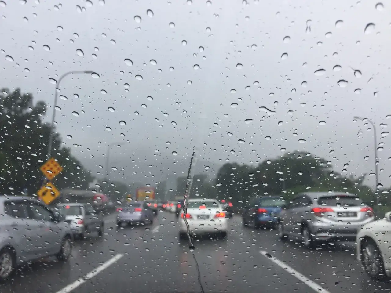 Deszcz na szybie, samochody stoją w korku. Uważaj na aquaplaning, co to zjawisko, gdy opony tracą przyczepność na mokrej nawierzchni.