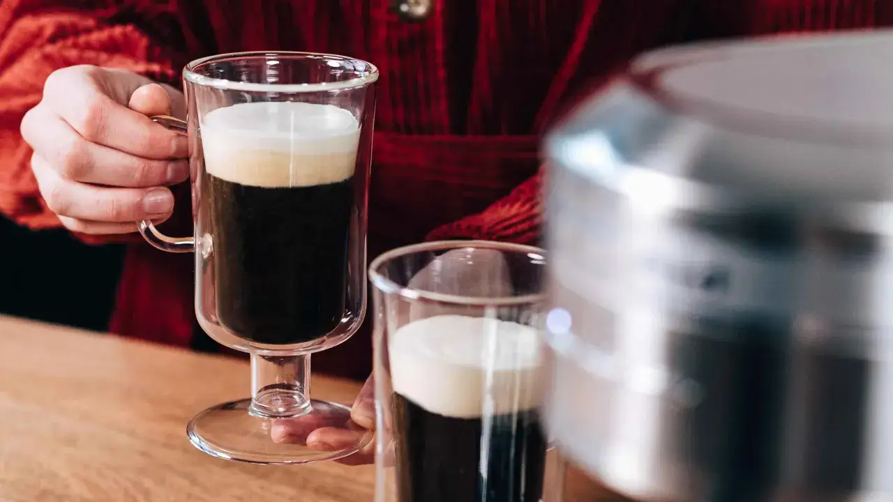 En person h&aring;ller ett glas iskaffe med gr&auml;dde. Ett enkelt iskaffe recept f&ouml;r en varm sommardag.