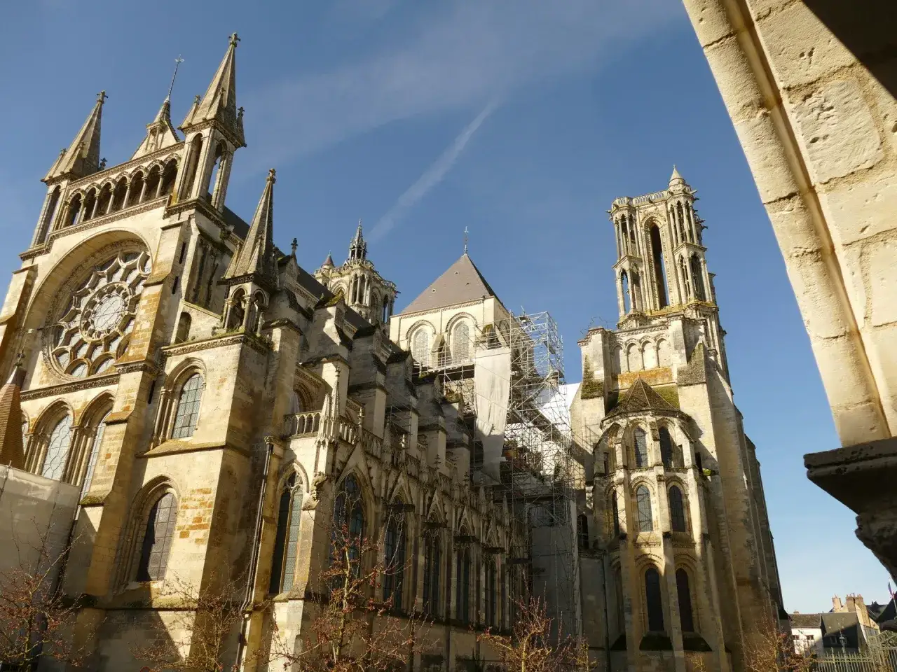 La **cath&eacute;drale de Laon**, majestueuse et ancienne, se dresse sous un ciel bleu. Des &eacute;chafaudages entourent une partie de sa structure, t&eacute;moignant de sa pr&eacute;servation.