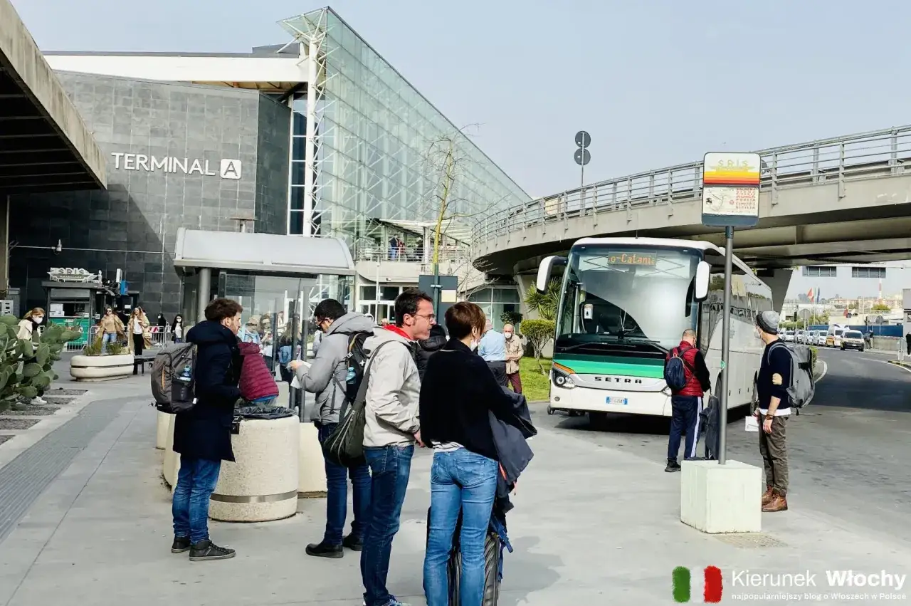 Ludzie czekają na autobus przed Terminalem A na lotnisku w Katanii.