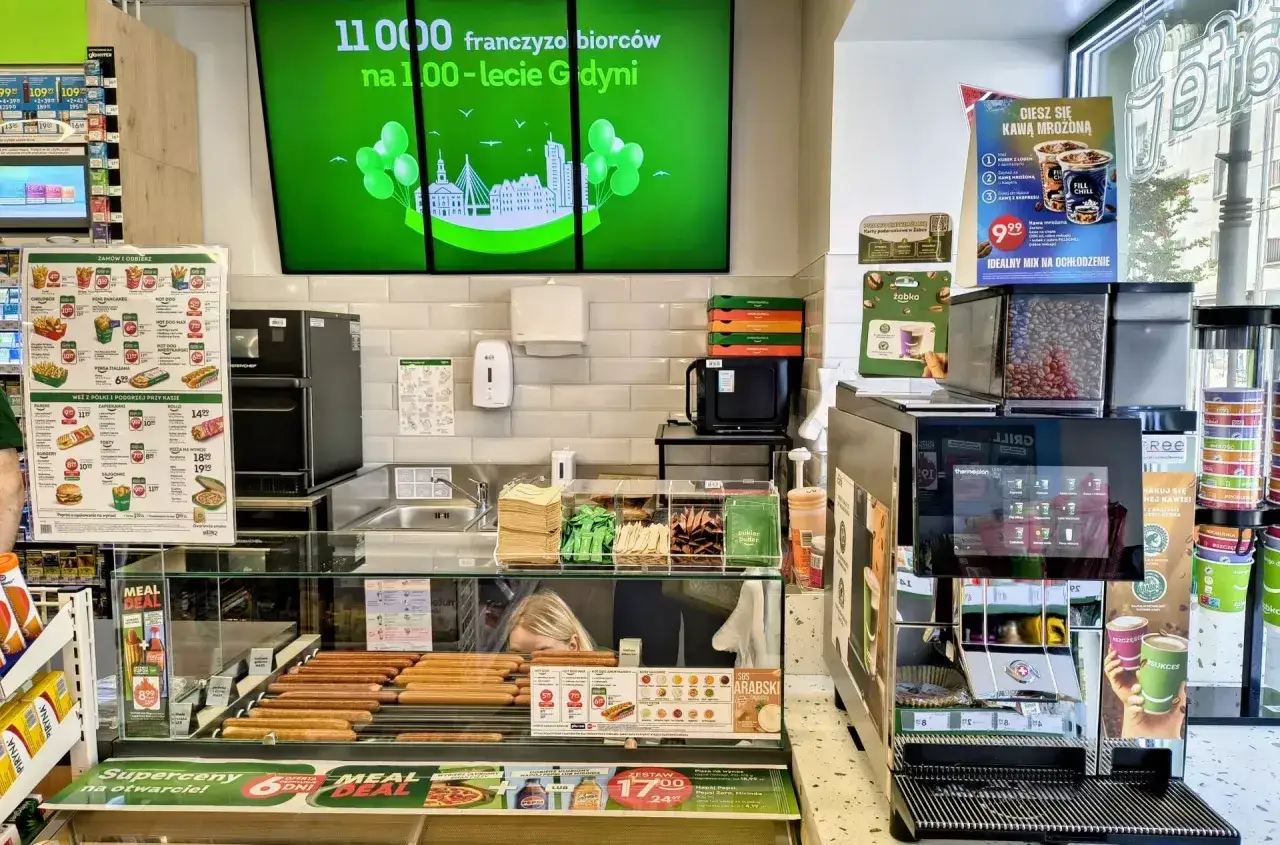 W sklepie Żabka franczyza gorące parówki i kawa mrożona czekają na klientów.