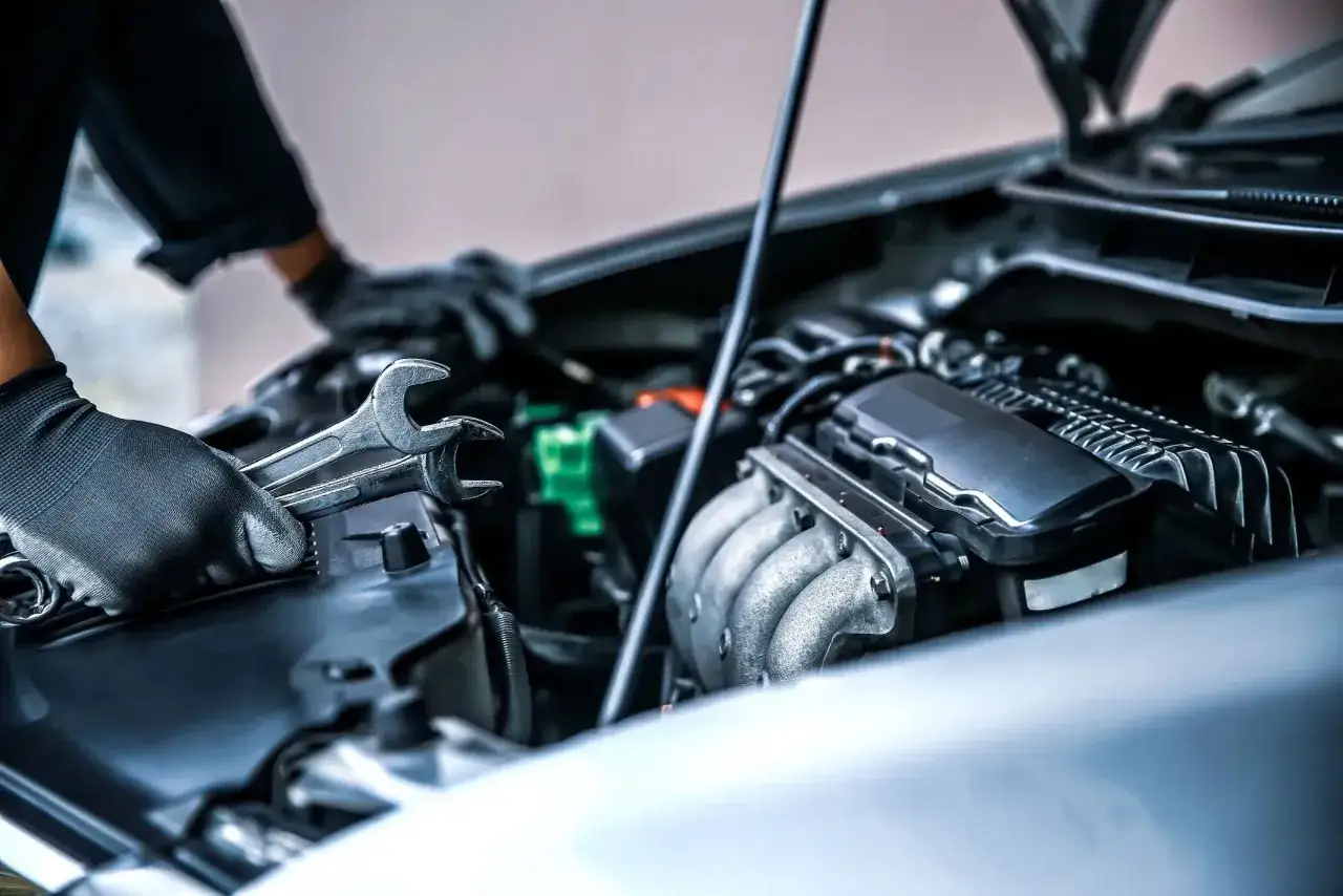 Mechanik sprawdza silnik benzynowy, który szarpie przy dodawaniu gazu. Klucze w dłoniach wskazują na diagnozę problemu.