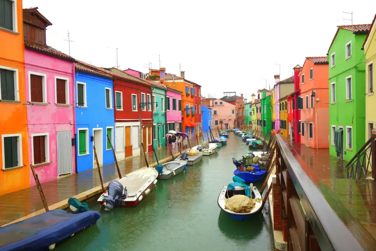 Les maisons color&eacute;es de l'&icirc;le de Burano bordent un canal o&ugrave; flottent des bateaux.