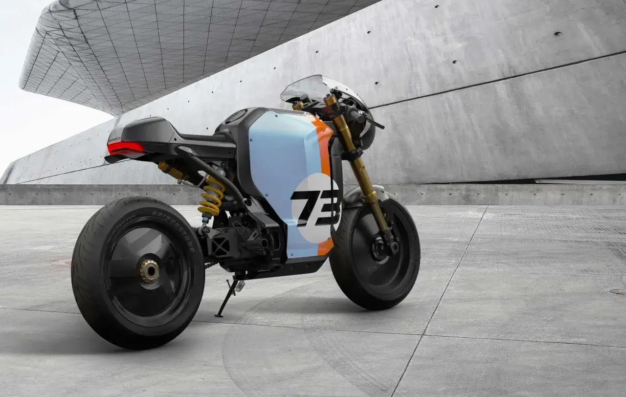 Una moto custom eléctrica con diseño deportivo y número 73 en la carrocería, estacionada en un entorno moderno de concreto.