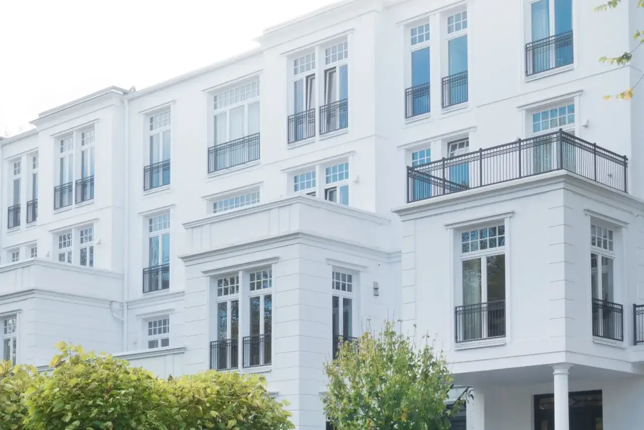 Modernes Mehrfamilienhaus mit weißen Fassaden und Balkonen. Ideal, wenn Sie ein Mehrfamilienhaus verkaufen möchten.