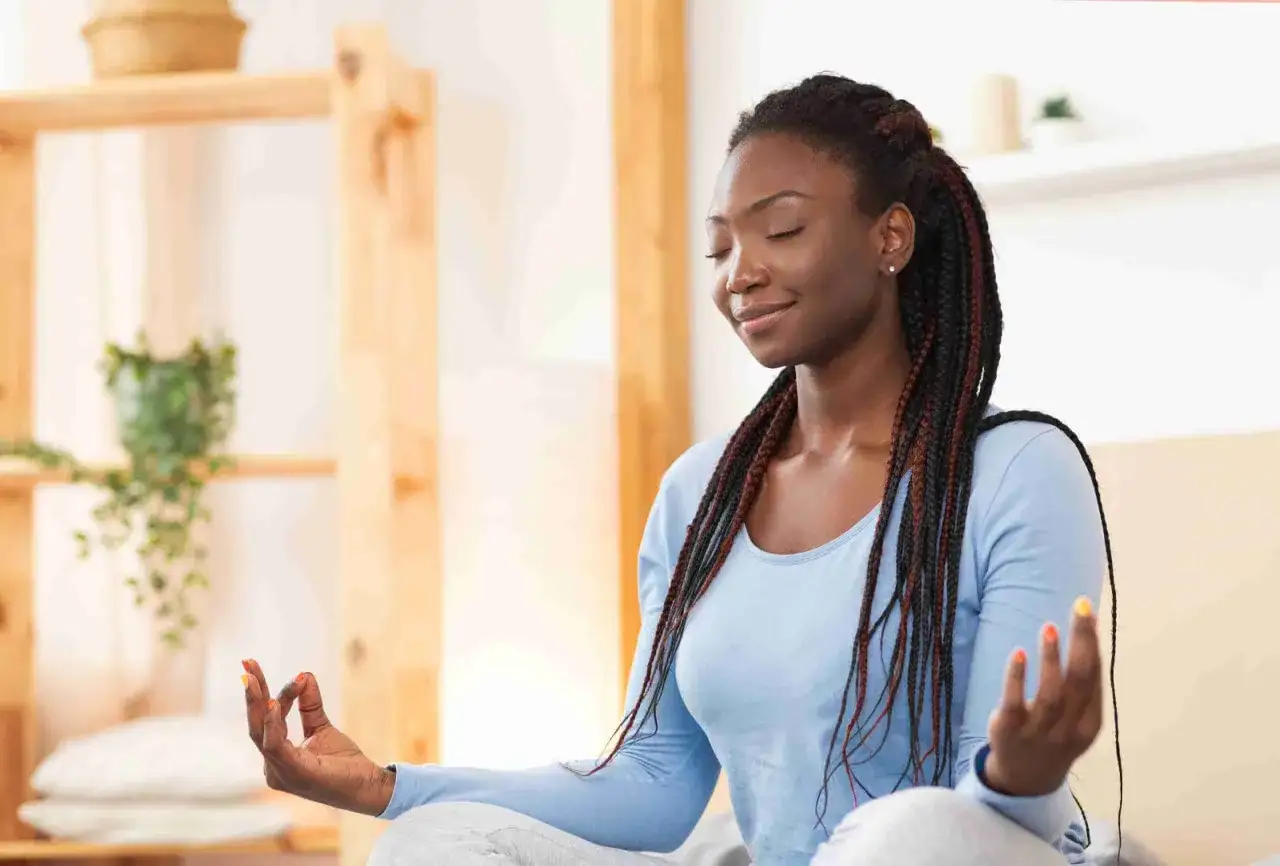 Mujer meditando con los ojos cerrados, practicando mantras poderosos en español para encontrar la paz interior.