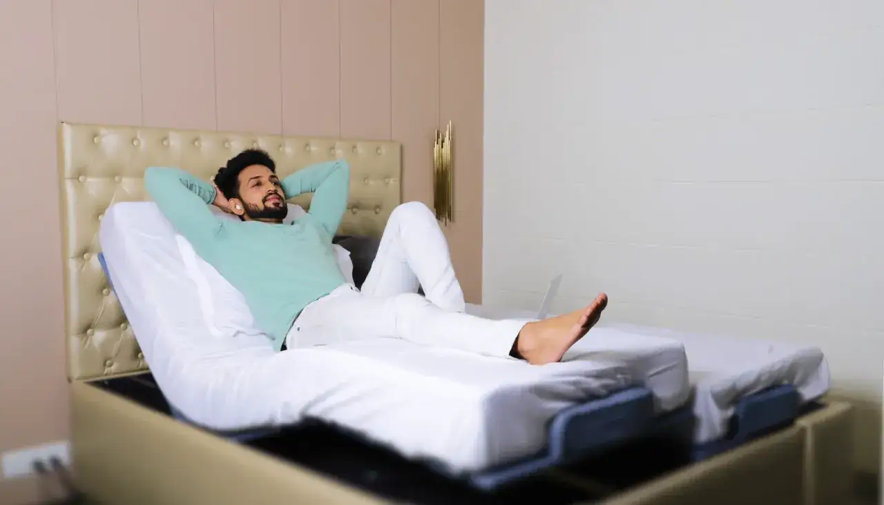A man relaxes on an adjustable bed, pondering if a bad mattress can cause leg pain.