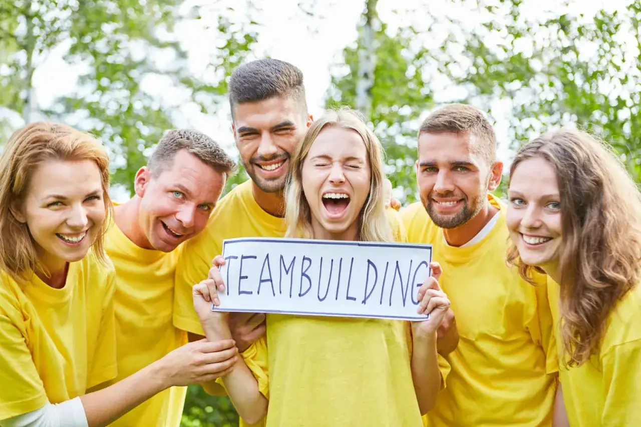 Glad grupp i gula tr&ouml;jor h&aring;ller upp en skylt med texten 