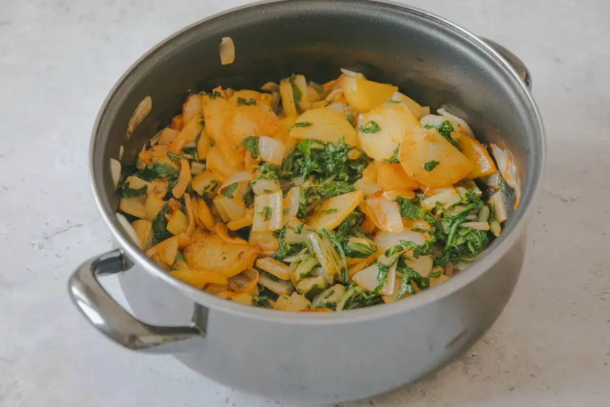 Un plato de acelgas a la extremeña recién hecho en una olla, con patatas y cebolla.