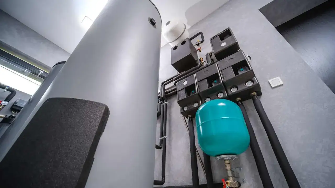 Großer Warmwasserspeicher mit angeschlossener Technik. Ein Druckausgleichsbehälter in Türkis ist Teil des Systems.