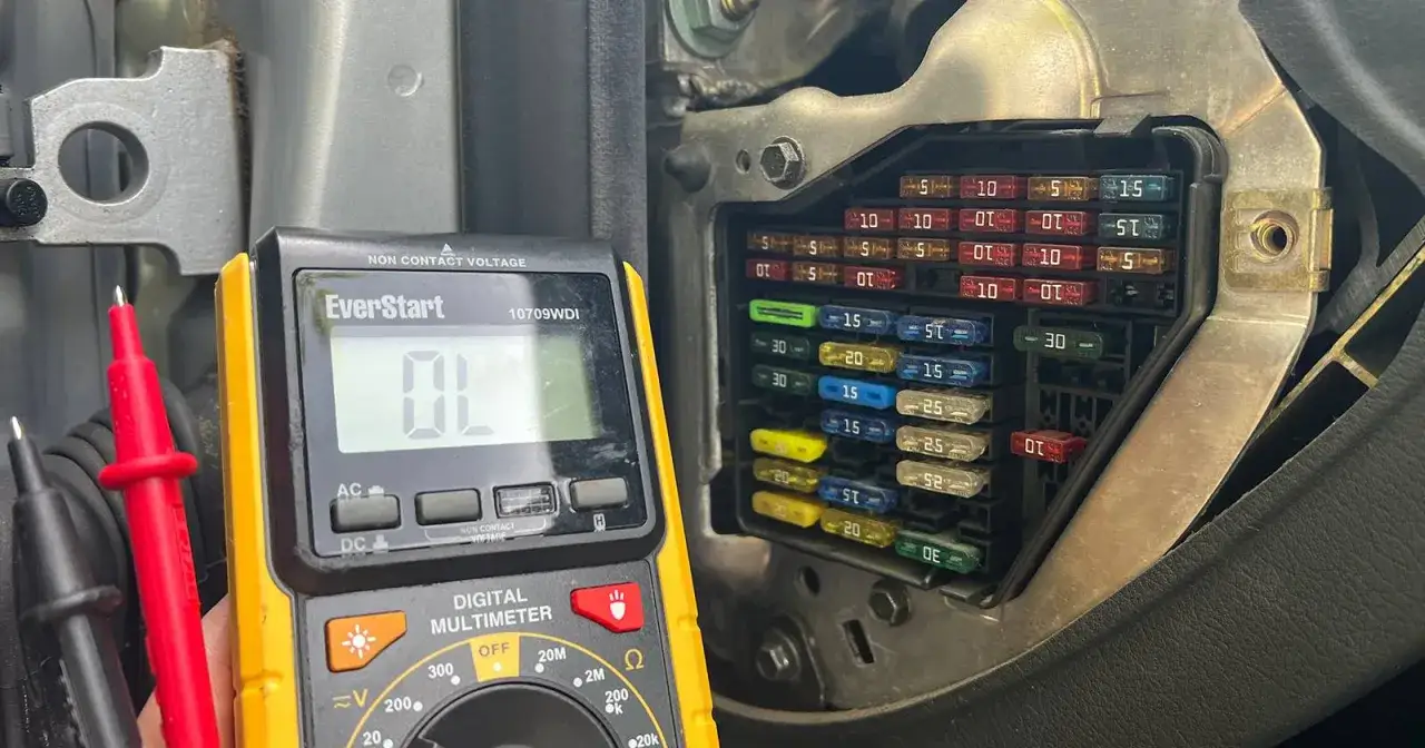 Multimeter shows OL, indicating a blown fuse in the car's fuse box.