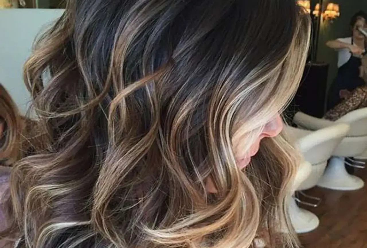 Melena castaña con mechas rubias que aportan luz y movimiento. Un estilo moderno y favorecedor.