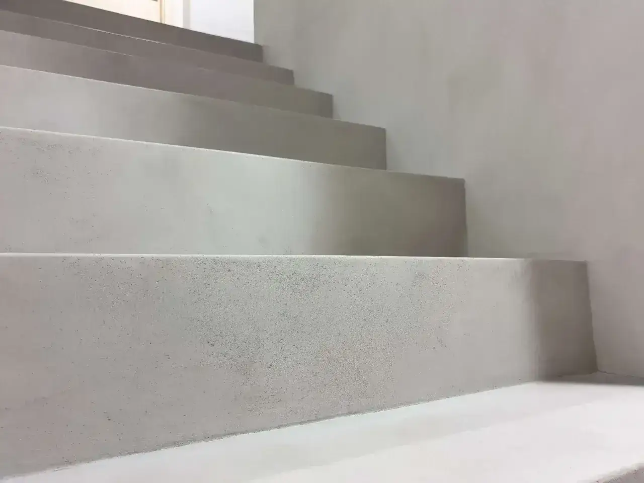Nowoczesny beton na klatce schodowej, minimalistyczne stopnie prowadzące w górę.