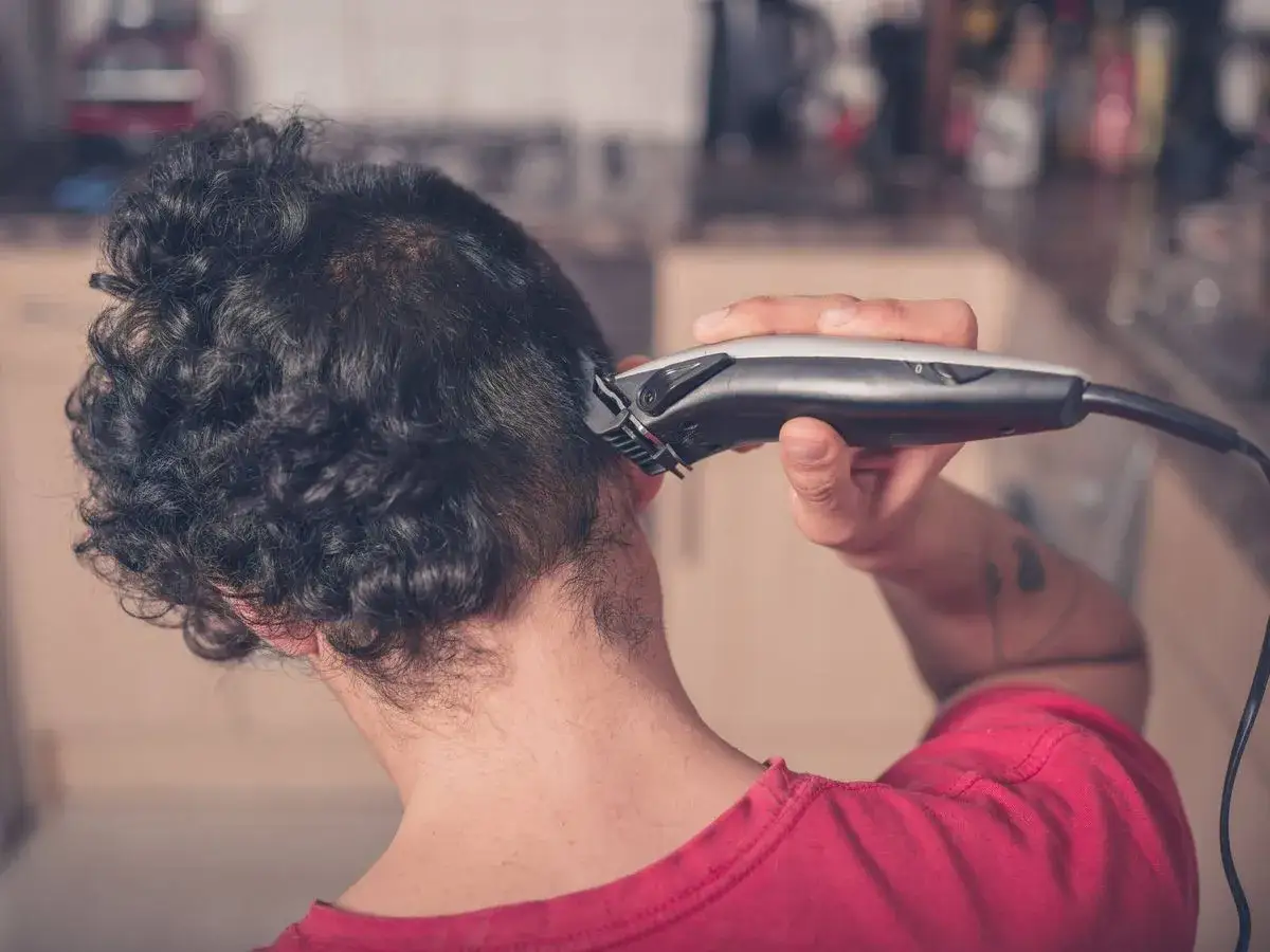 Hombre se corta el pelo con m&aacute;quina, mostrando c&oacute;mo cortar el pelo con m&aacute;quina en casa.