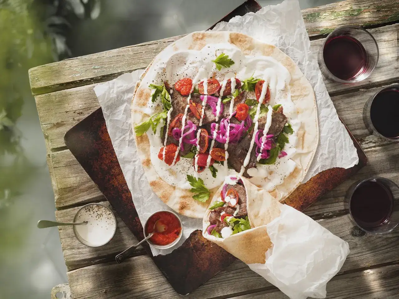 En läcker kyckling kebab på ett plattbröd med tomater, lök och vit sås. En annan kebabrulle ligger bredvid.
