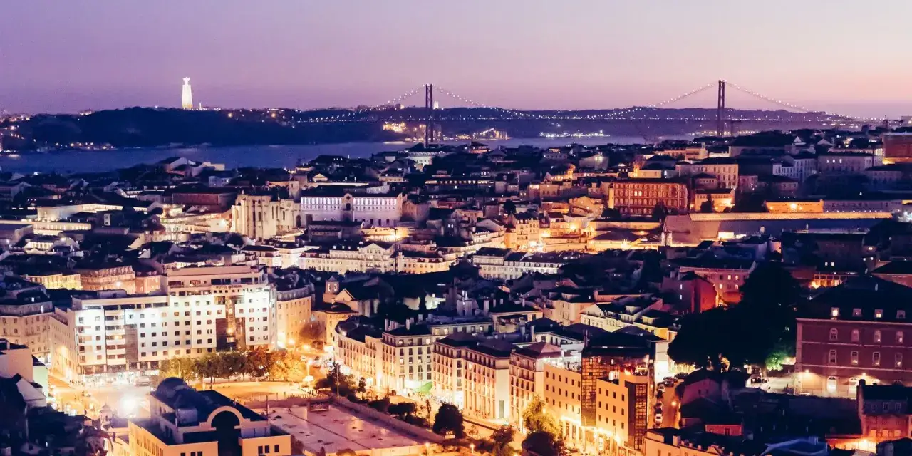 Lichtermeer der schönsten Stadt Portugals, Lissabon, bei Nacht. Die Brücke des 25. April und die Christusstatue im Hintergrund.