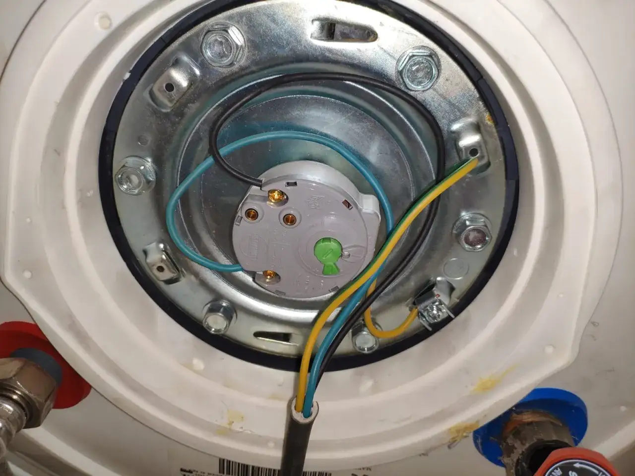 Vue rapprochée du câblage d'un chauffe-eau. Un fil vert/jaune est mal connecté, ce qui pourrait causer un chauffe eau qui fait disjoncter.