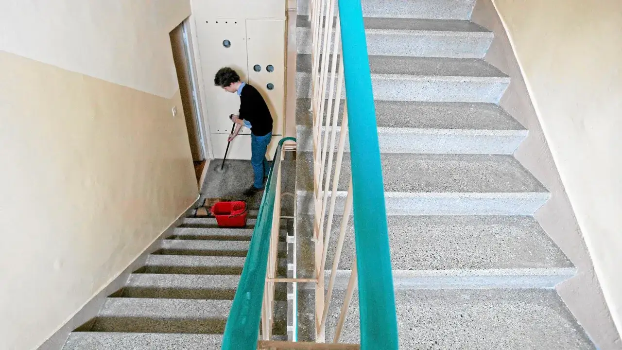 Osoba sprząta klatkę schodową. Sprawdź sprzątanie klatek schodowych cennik, by dowiedzieć się, ile kosztuje utrzymanie czystości.