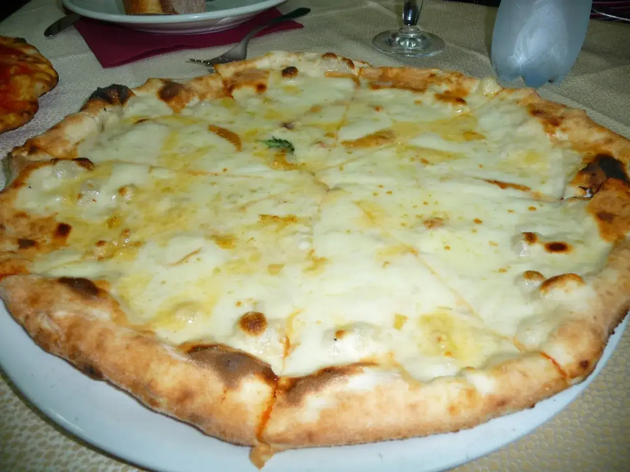 Pizza 4 formaggi appena sfornata, con crosta dorata e abbondante formaggio filante.