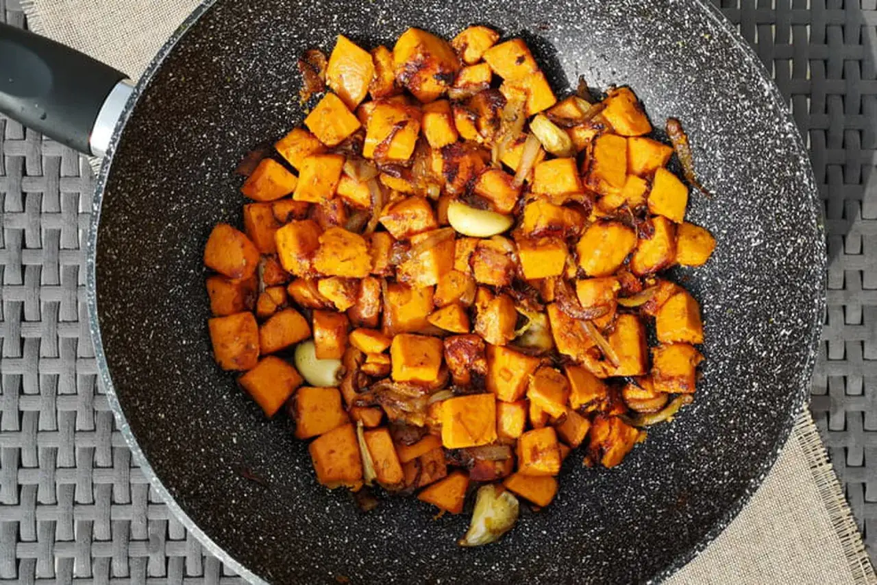 Poêlée de patates douces coupées en dés, oignons et ail. Une recette patate douce rapide et savoureuse, prête à être dégustée.