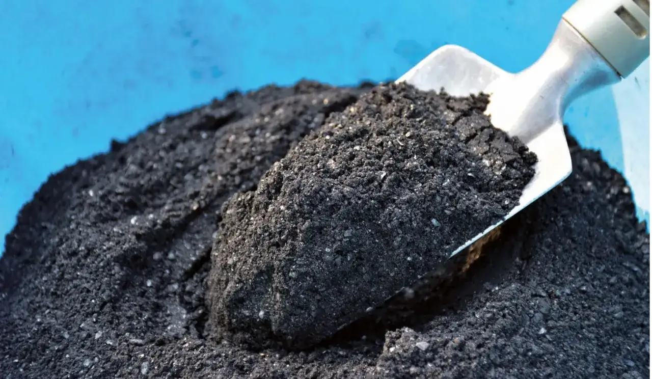 Una pala recoge una porci&oacute;n de biochar, un carb&oacute;n vegetal que mejora la tierra.