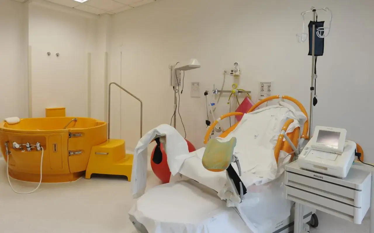 Sala parto con vasca gialla e letto attrezzato, pronta per un parto distocico.