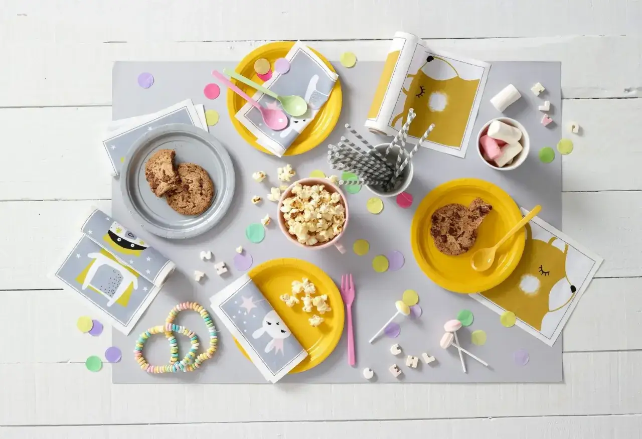 Mesa lista para un picoteo de cumplea&ntilde;os infantil: galletas, palomitas, caramelos y servilletas con divertidos dise&ntilde;os de animales.