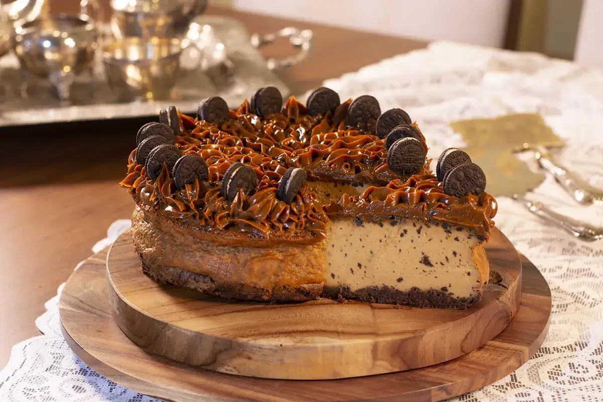 Delicioso pastel de oreo con dulce de leche y galletas enteras, servido en tabla de madera.