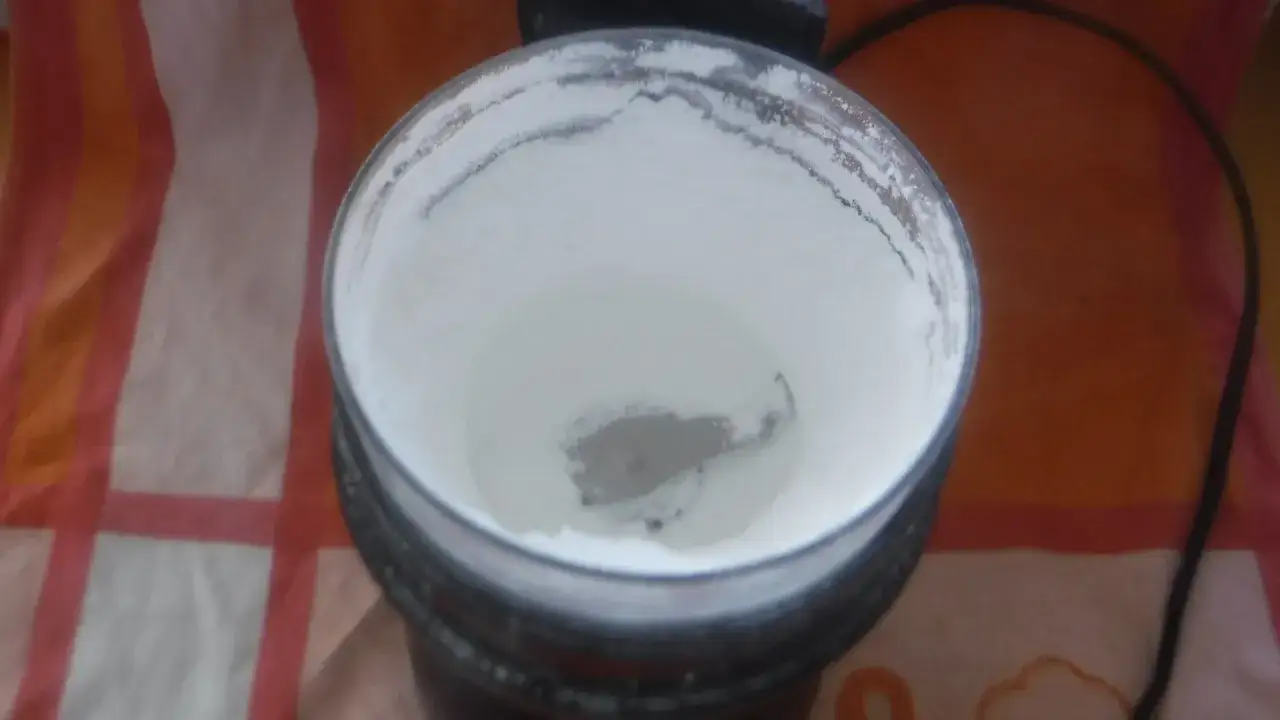 Młynek z białym proszkiem, gotowy do zmielenia cukru na puder. Prosty sposób, jak zrobić cukier puder w domu.